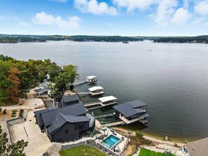 Una propiedad frente al lago con varias lanchas amarradas, piscina y vista al lago.