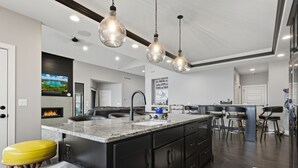 Una cucina moderna con una grande isola, mobili neri e illuminazione a sospensione.