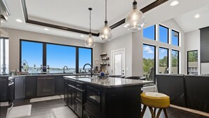 Una cucina moderna con una grande isola, mobili scuri e luci a sospensione.