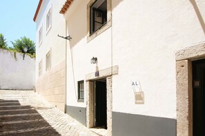 A narrow cobblestone alley with a building featuring a door marked with the number 12, a small window, and a sign with the letters 'AL' on the wall. - Nomad s Castel Lisbon - The Solo (Lisbon)
