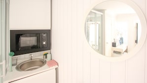 A kitchen with a microwave, sink, and a round mirror. - Nomad s Castel Lisbon - The Solo (Lisbon)