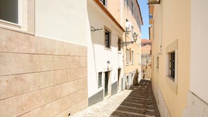 A narrow cobblestone street between buildings with windows and a street lamp. - Nomad s Castel Lisbon - The Solo (Lisbon)