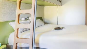Una cama individual con escalera, una mesita de noche con lámpara, y una cama con almohada y un libro.