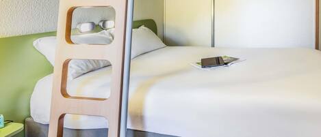 Un lit superposé avec une échelle, une table de chevet avec une lampe et un lit avec un oreiller et un livre.