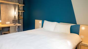 Una habitación de hotel con una cama, un escritorio y una silla.