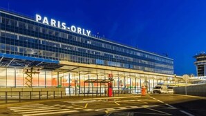 Un edificio moderno con señalización 'PARIS-ORLY', con fachada de vidrio y una zona de entrada cubierta.