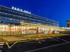 A modern building with 'PARIS-ORLY' signage, featuring a glass facade and a covered entrance area.