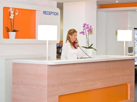 A reception desk with a 'RECEPTION' sign, a potted orchid, and a telephone.