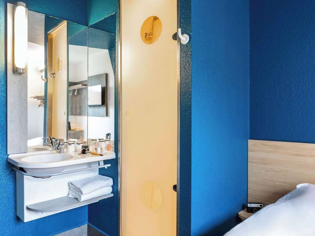 Een badkamer met een wastafel, spiegel en douche.