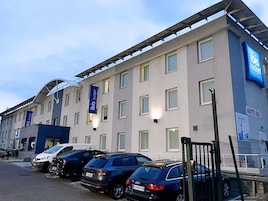 A hotel with multiple parking spaces, a modern facade, and a prominent 'ibis budget' sign.