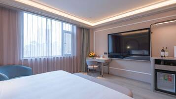 Een hotelkamer met een bed, bureau, televisie en minibars.