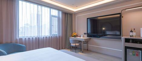 Una habitación de hotel con cama, escritorio, televisor y minibar.
