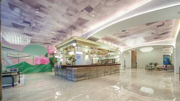 A modern lobby with a reception desk, seating area, and a mural.