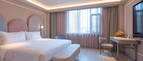 A hotel room with a large bed, a desk, a chair, and a TV.