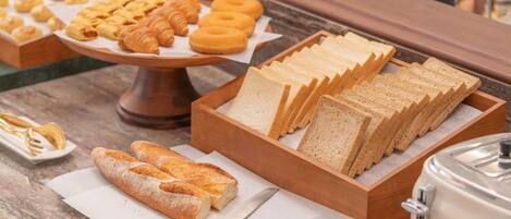 A breakfast buffet with bread, pastries, and a toaster.