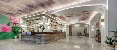 A hotel lobby with a reception desk, seating area, and a decorative ceiling.