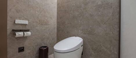 Ein modernes Badezimmer mit Toilette, Mülleimer und Papierhandtuchspender.