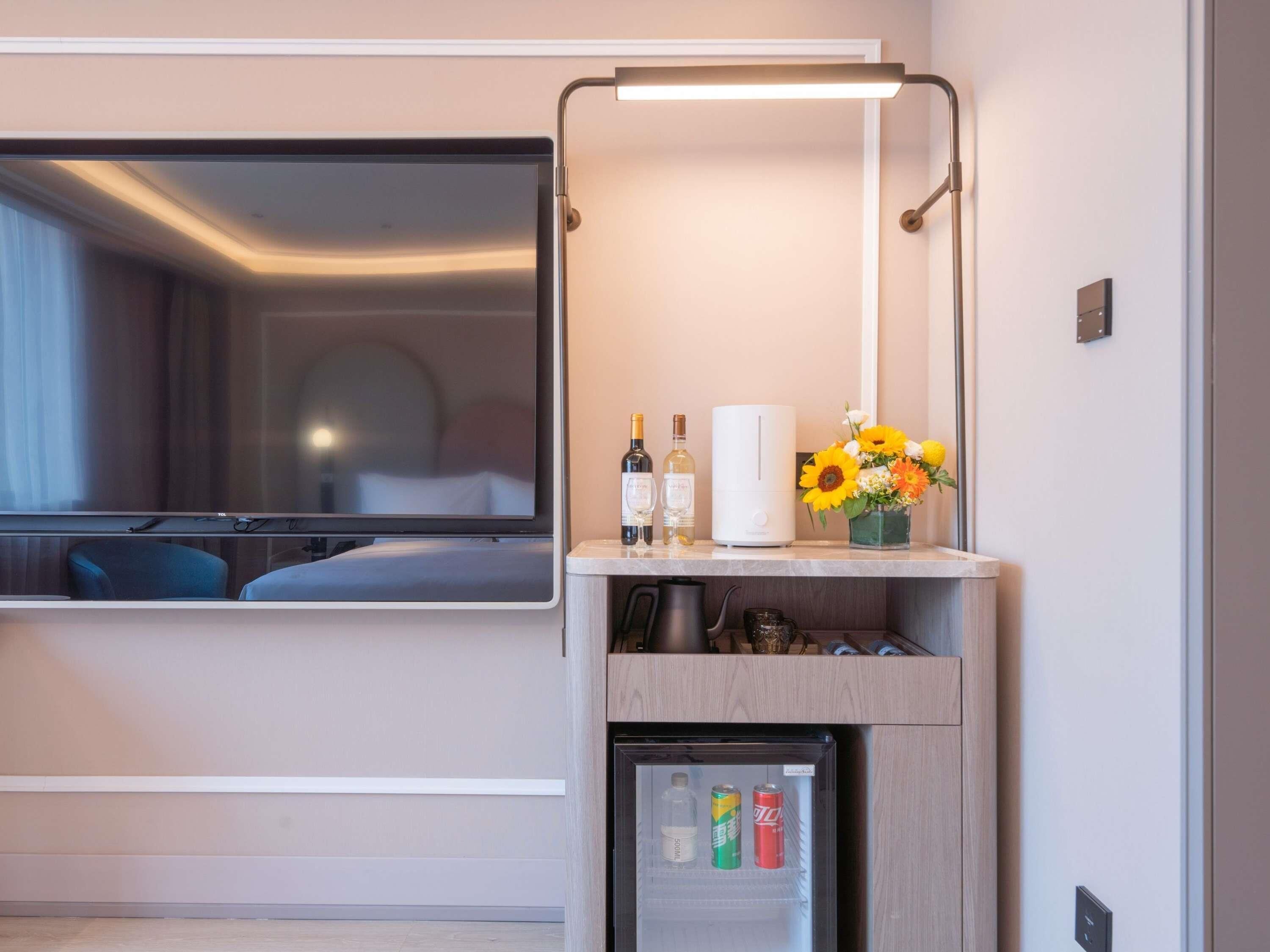 A hotel room with a bed, a TV, a minibar, a refrigerator, and a window.