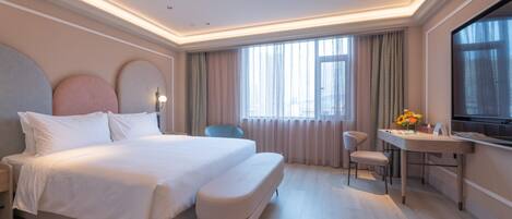 A modern hotel room with a large bed, a desk, and a television.