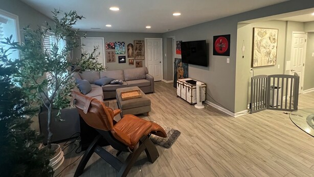 A living room with a sectional sofa, a recliner, a television, and a wall-mounted TV.