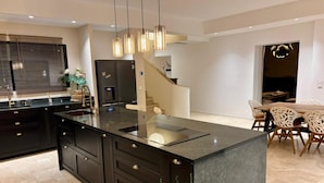 Una cocina moderna con una isla central, armarios negros e iluminación colgante.