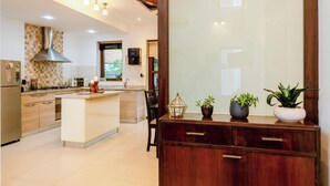 A modern kitchen with a central island, wooden cabinets, and a built-in stove. - Staymaster Water Wave 3BR Villa  (Vagator)