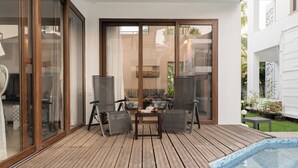 A covered outdoor area with a pool, sliding glass doors, and a table with chairs. - Staymaster Water Wave 3BR Villa  (Vagator)