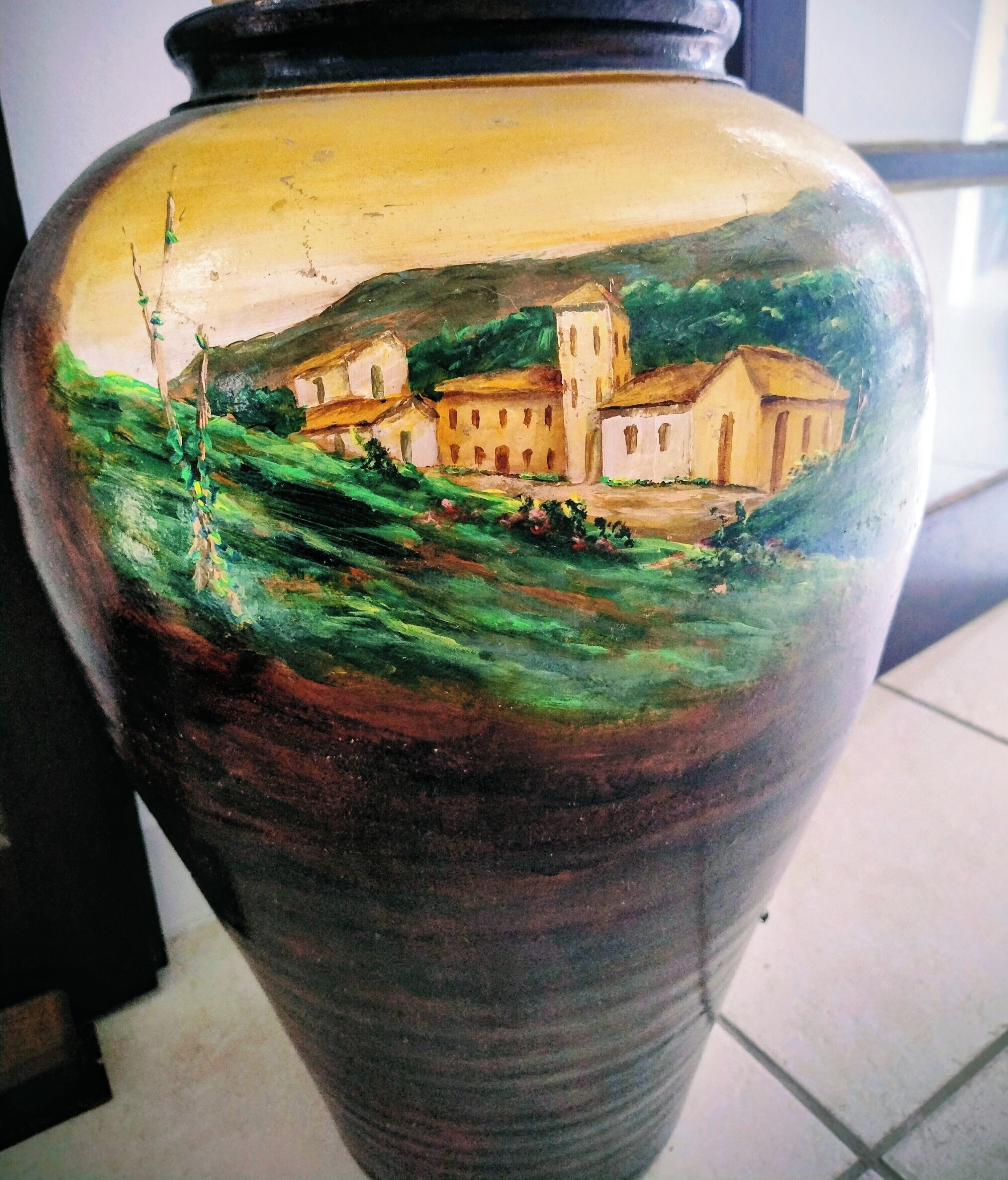 Un jarrón de cerámica grande con un paisaje pintado.