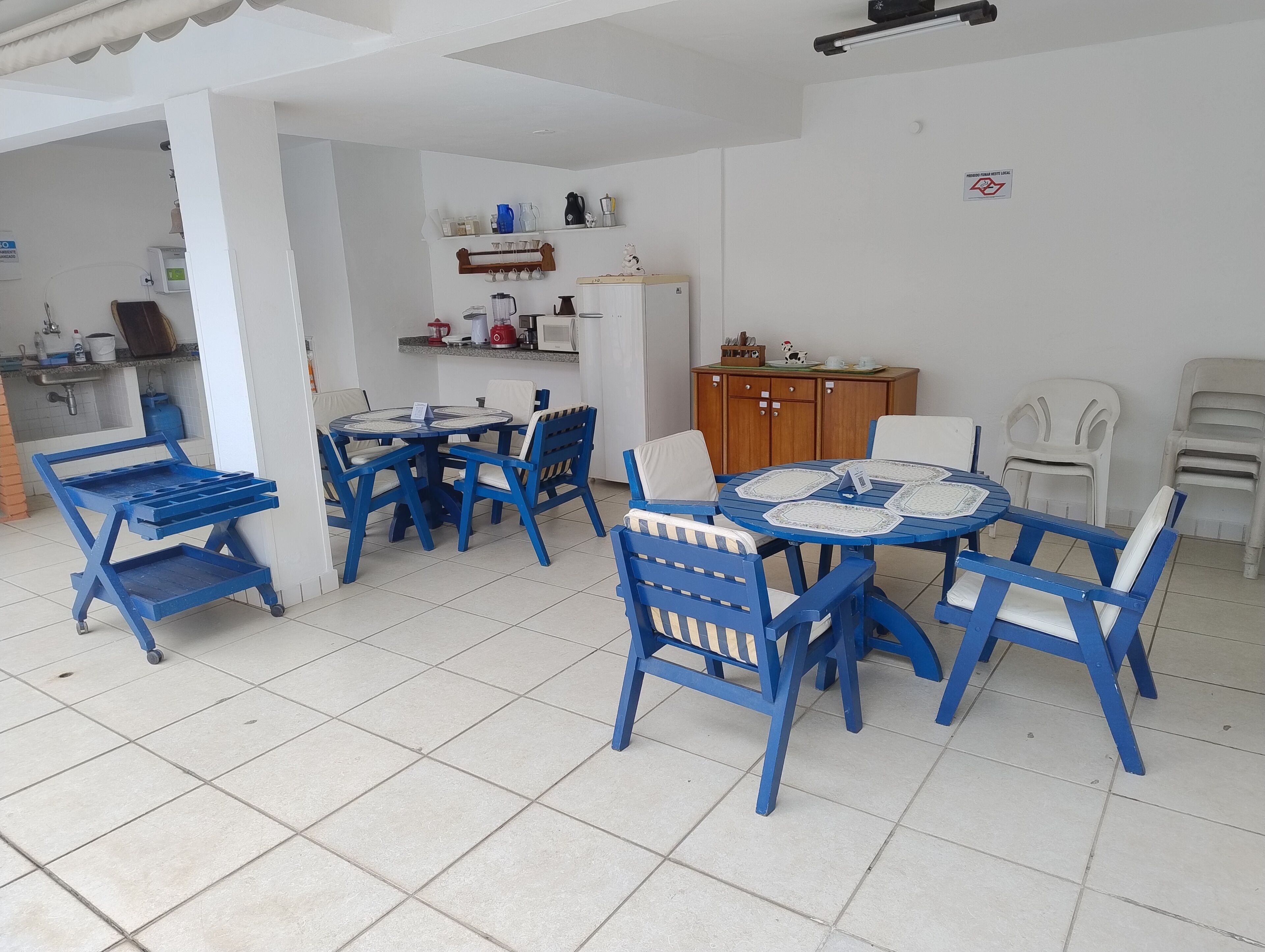 A dining area with blue chairs and a round table, a kitchen area with a sink and cabinets, and a ceiling fan.