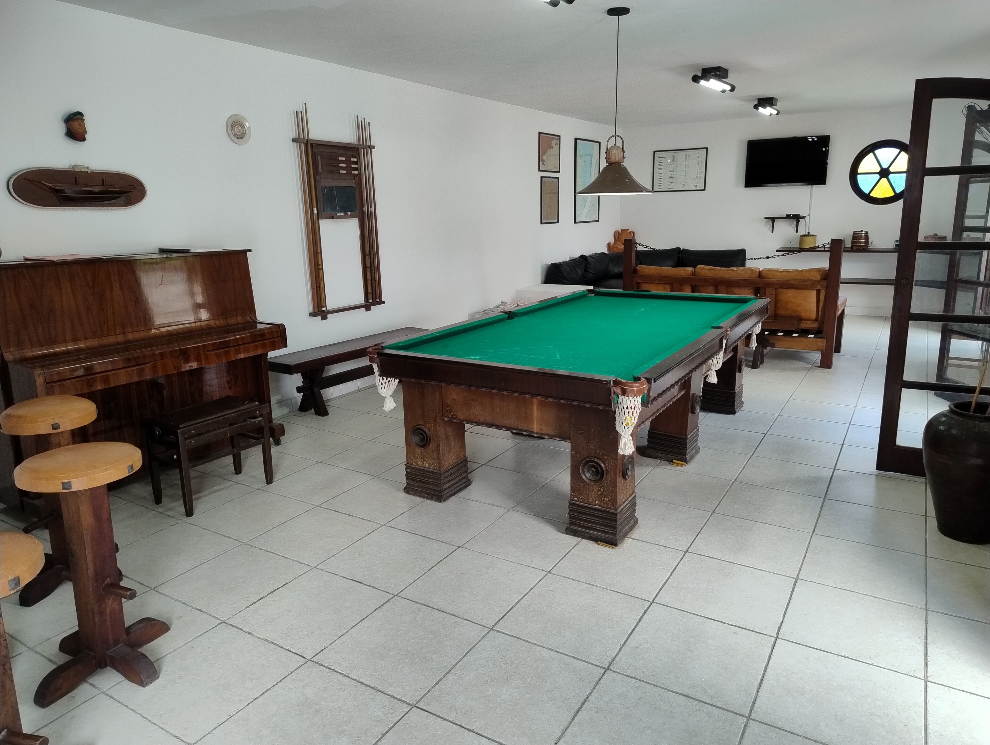 Una sala biliardo con tavolo da biliardo, mobili in legno e televisore.