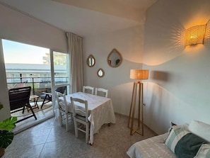 Ein Zimmer mit Esstisch, Stühlen, einer Couch, einer Lampe und Blick durch eine Glastür.
