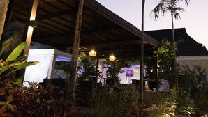 A modern building with a covered patio area, surrounded by palm trees and plants. - SeaLord Resort Karu (Abuja)