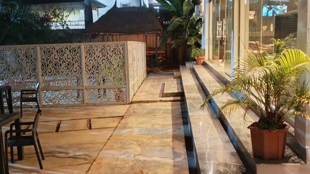 A paved outdoor area with a seating arrangement, a decorative fence, and potted plants. - SeaLord Resort Karu (Abuja)