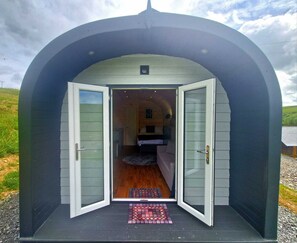Une petite structure fermée, dotée d’un seul lit et d’une porte, et offrant une vue dégagée sur l’intérieur.