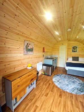 A cozy cabin with wooden walls, a kitchen area, a bed, and a small rug. - The Star Inn (Llanbrynmair)