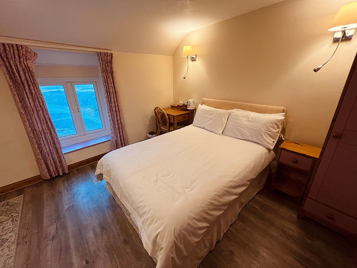 A bedroom with a bed, bedside tables, a window with curtains, and a lamp.
