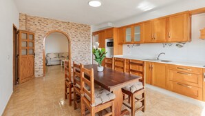 A spacious kitchen with wooden cabinets, a dining area with a table and chairs, and a brick wall.