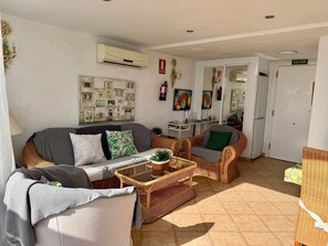 A living room with a sofa, chairs, a coffee table, and a wall-mounted air conditioner. - 1.Skol Marbella 703A (Marbella)