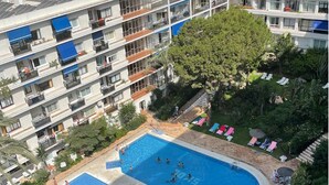 Ein mehrstöckiges Hotel mit Schwimmbad, Liegestühlen und einem Garten.