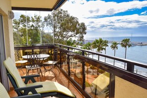 Ein Balkon mit Gartenmöbeln, Blick auf das Meer und Palmen.