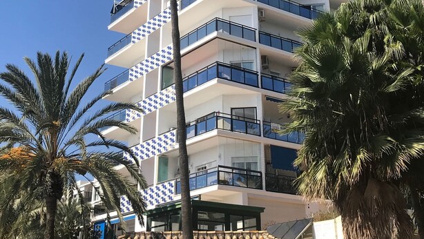 A multi-story hotel with balconies, palm trees, and a clear blue sky. - 1.Skol Marbella 811A (Marbella)