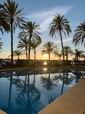 A swimming pool with palm trees and a sunset in the background. - 1.Skol Marbella 811A (Marbella)