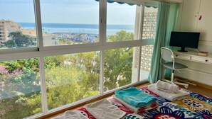 Een kamer met een groot raam, een bureau met een computer en een bed met handdoeken.