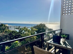 Ein Balkon mit Blick auf den Strand, ein Laptop und ein Blumentopf.