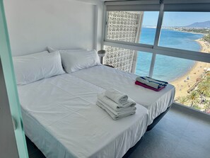 Ein Hotelzimmer mit einem großen Bett und Blick auf den Strand, mit einem weißen Vorhang.