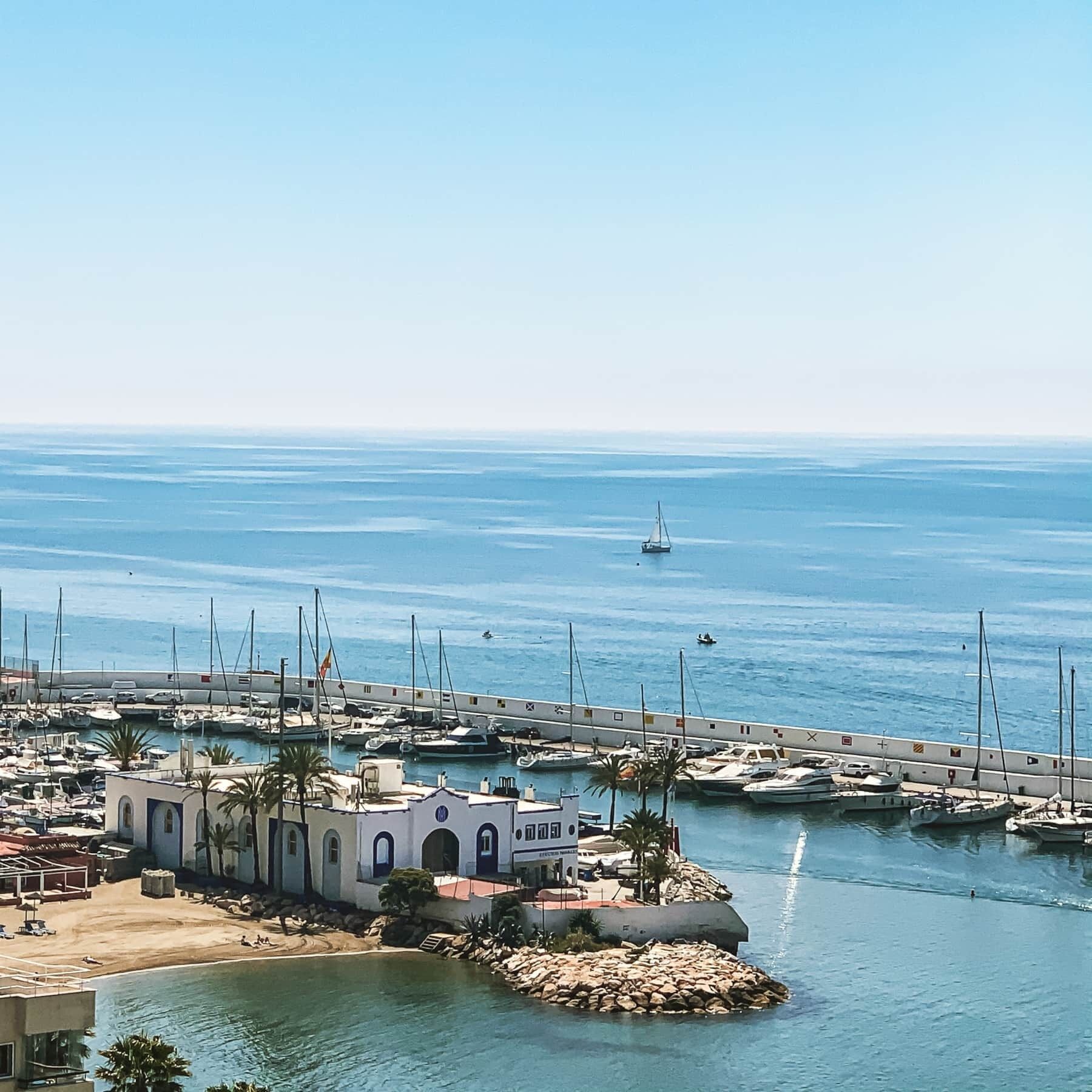 A marina with boats, a pier, and a building with a white facade and arched windows.