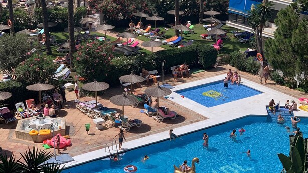 Et poolområde med flere swimmingpools, liggestole og parasoller.