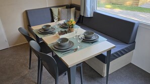 A dining area with a table set for four, a bench, and a window view. - Stijlvol Chalet in de Natuur van Twente! (Lattrop-Breklenkamp)