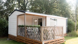 A small, single-story wooden cabin with a porch, surrounded by greenery. - Stijlvol Chalet in de Natuur van Twente! (Lattrop-Breklenkamp)