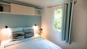 A bedroom with a bed, bedside lamps, a window with curtains, and a shelf above the bed. - Stijlvol Chalet in de Natuur van Twente! (Lattrop-Breklenkamp)